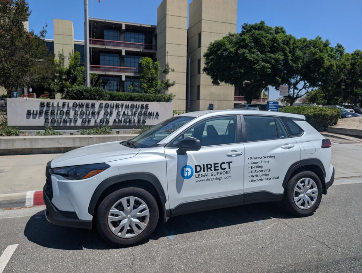 Direct Legal Support vehicle in front of the Bellflower Courthouse sign on Flower Street